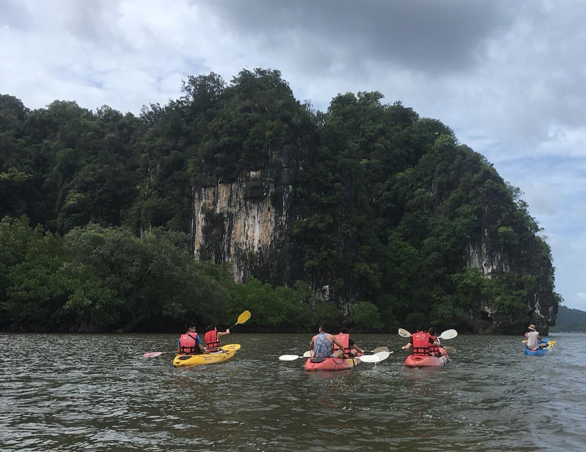 Kayakers on flat water beneath limestone cliffs at Ao Thalane, Krabi