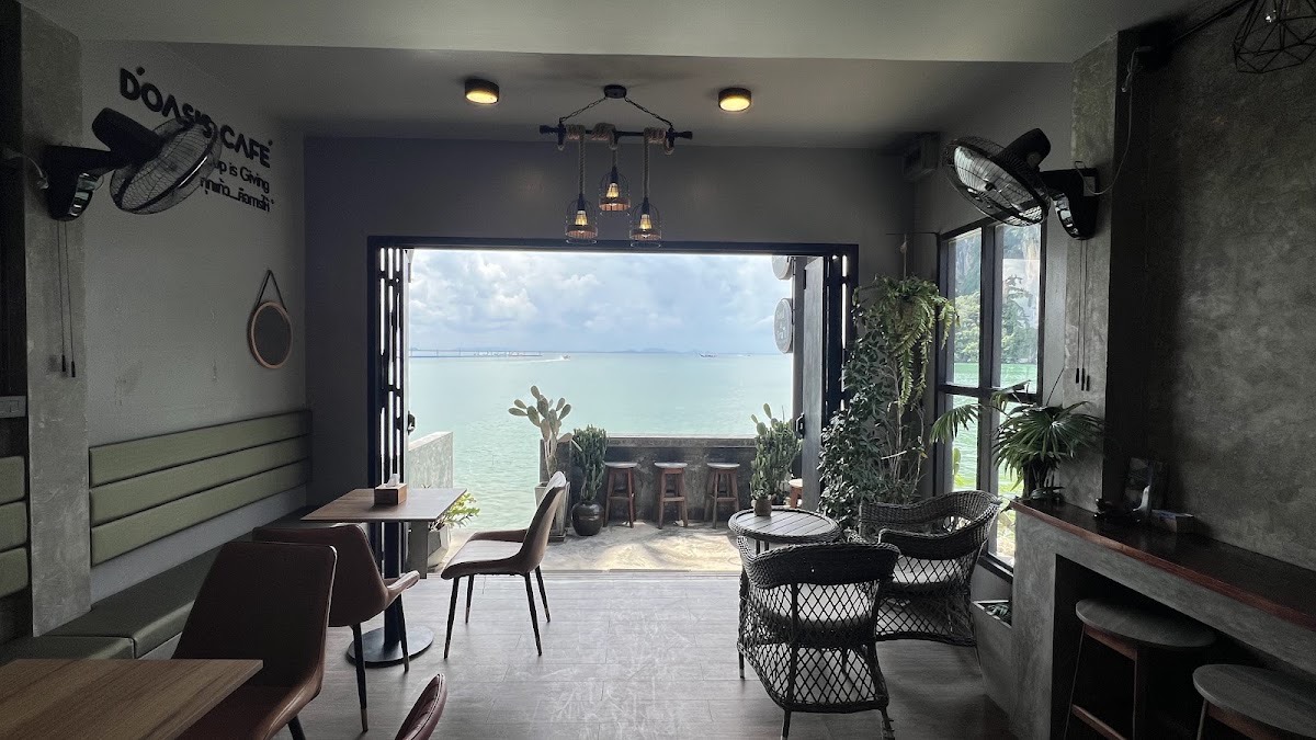 Interior of D'oasis cafe opening directly onto the sea, with plants and ceiling fans