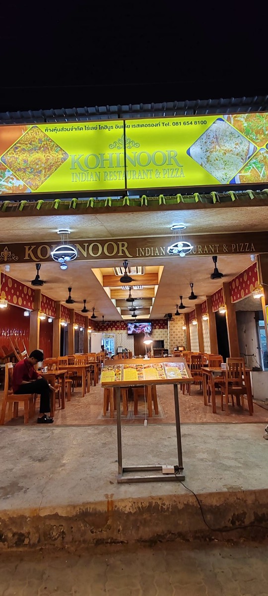 The lit Kohinoor Indian Restaurant and Pizza shopfront on Railay East at night