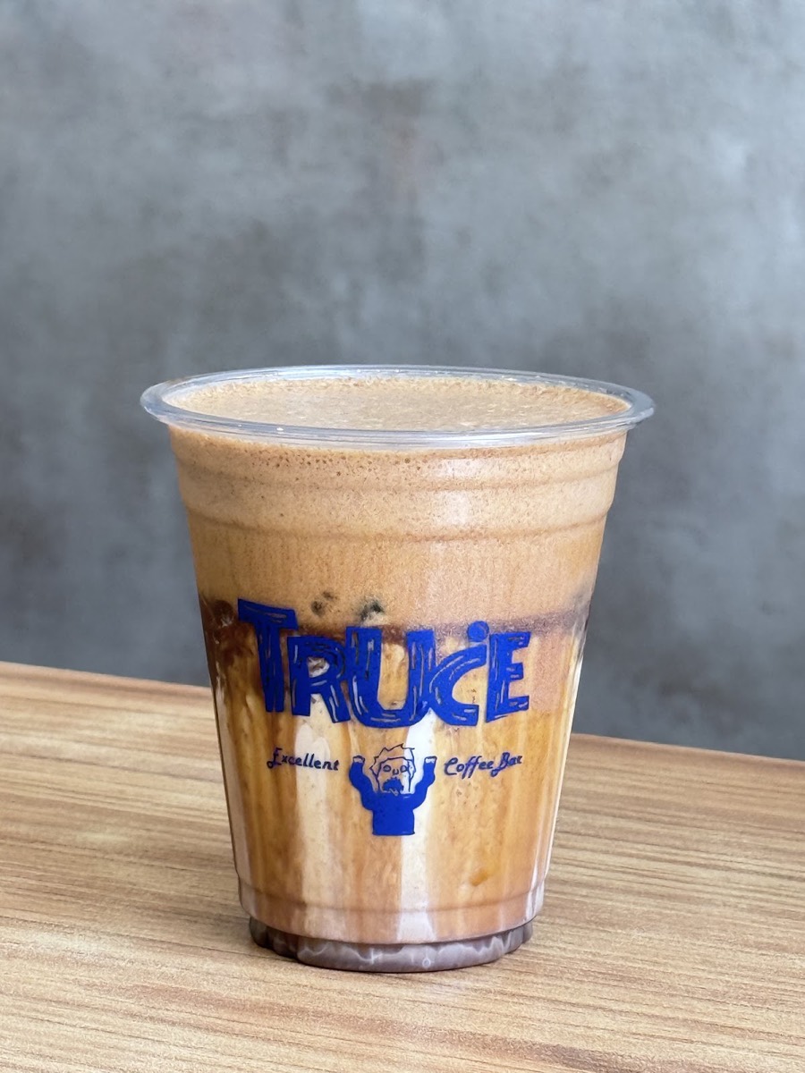 An iced coffee in a cup branded TRUCE Excellent Coffee Bar